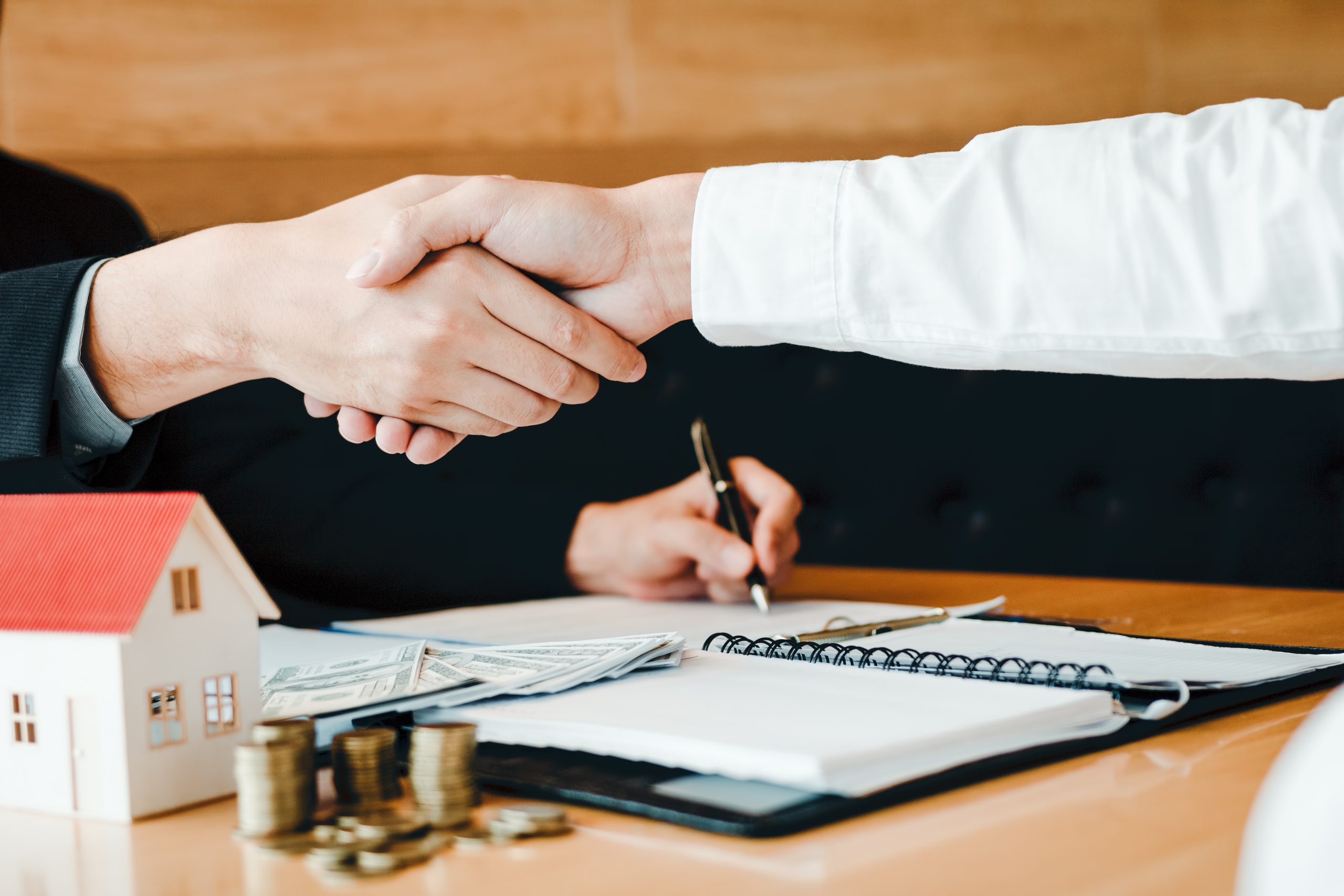 Home sales agents and buyers work on signing new homes and shaking hands.